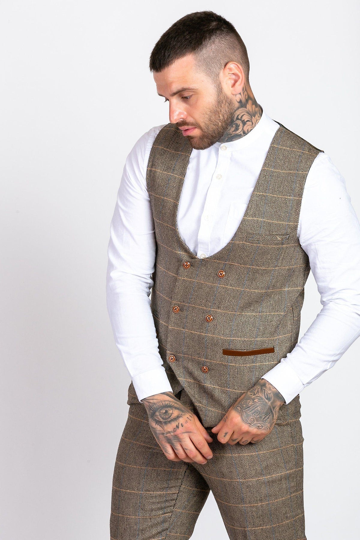 A man wearing the marcdarcy MAX Royal Blue Blazer with TED Waistcoat over a white shirt looks down, his neck and hand tattoos adding an edgy twist to his smart-casual look.