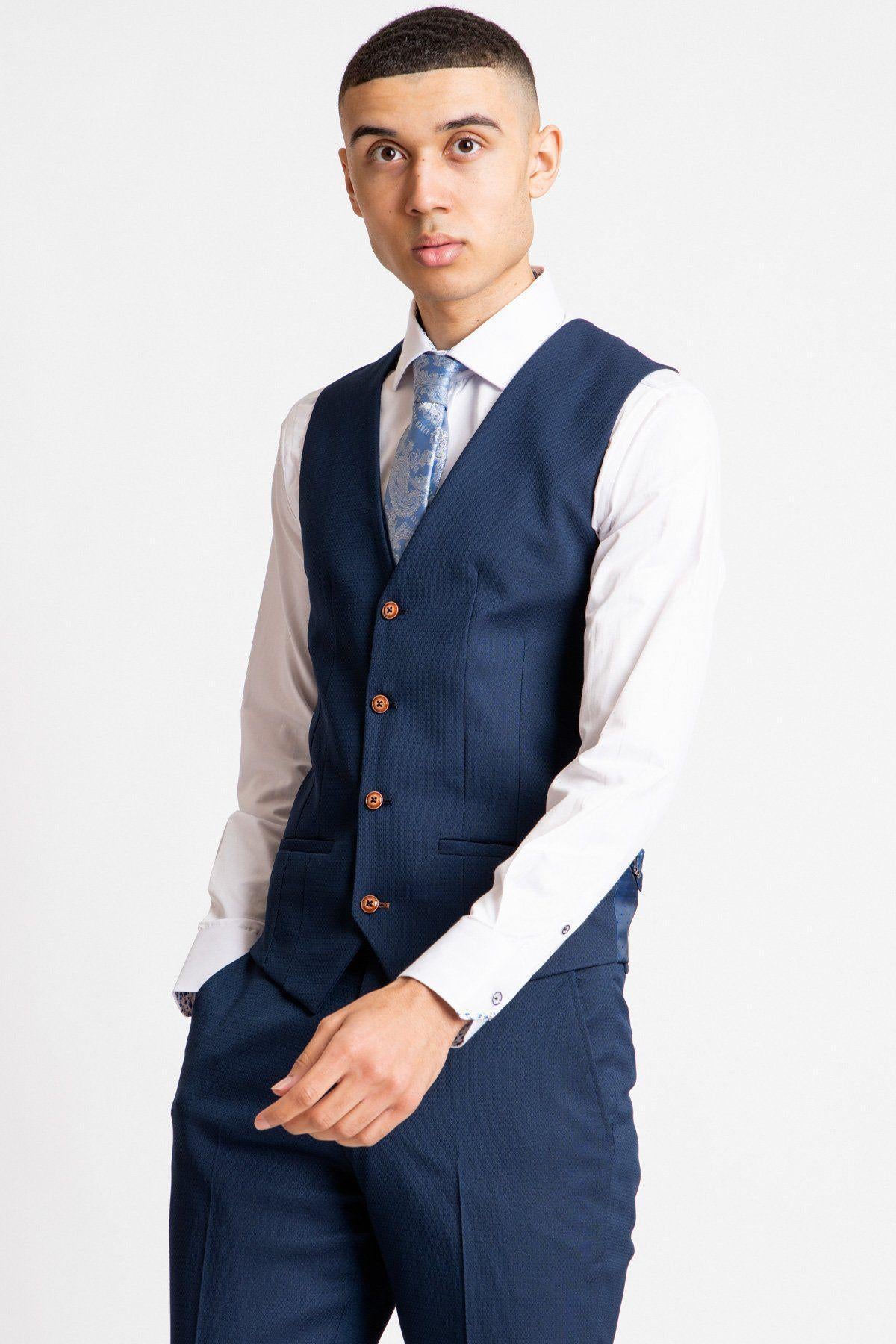 Dominic Calvert-Lewin models the marcdarcy MAX Royal Blue Suit from The Everton Collection, paired with a white shirt and light blue patterned tie, standing confidently with one hand in his pocket.