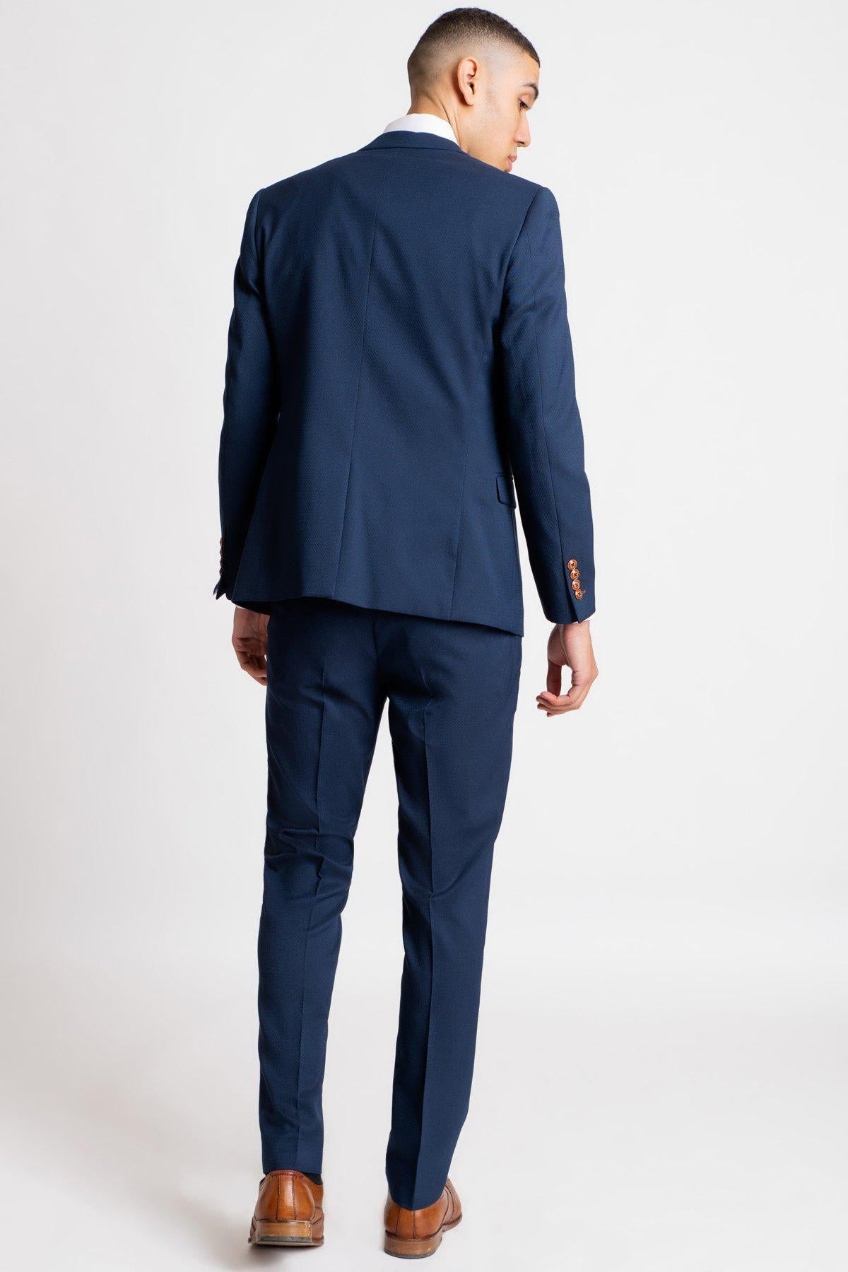 A man is seen from the back wearing marcdarcy’s The Everton Collection | Dominic Calvert-Lewin In The MAX Royal Blue Suit with a white shirt and brown shoes.