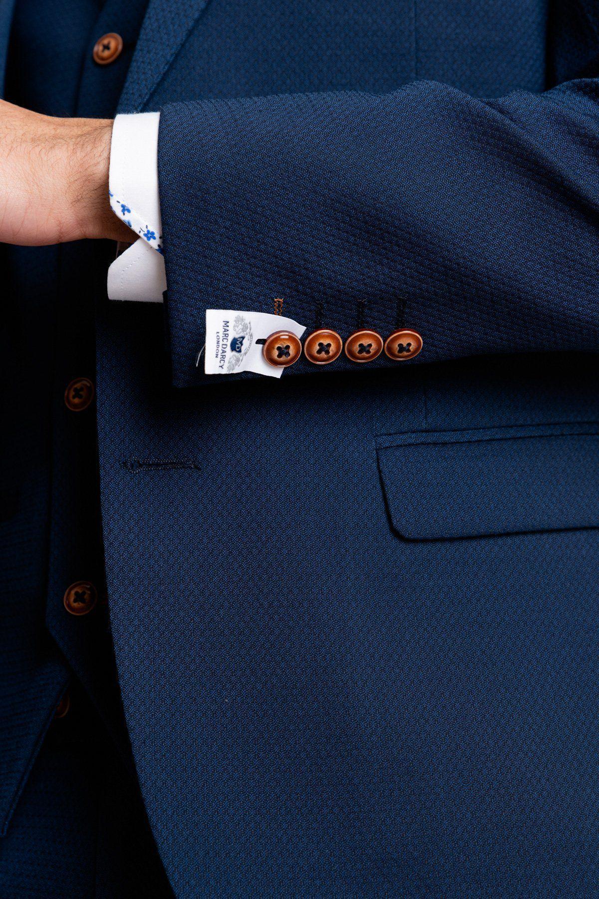 Close up of The Everton Collection | James Garner In The MAX Royal Blue Suit by marcdarcy, showing its textured royal blue fabric, brown buttons, and a blue floral white shirt cuff—a stylish slim fit blazer with visible branding.