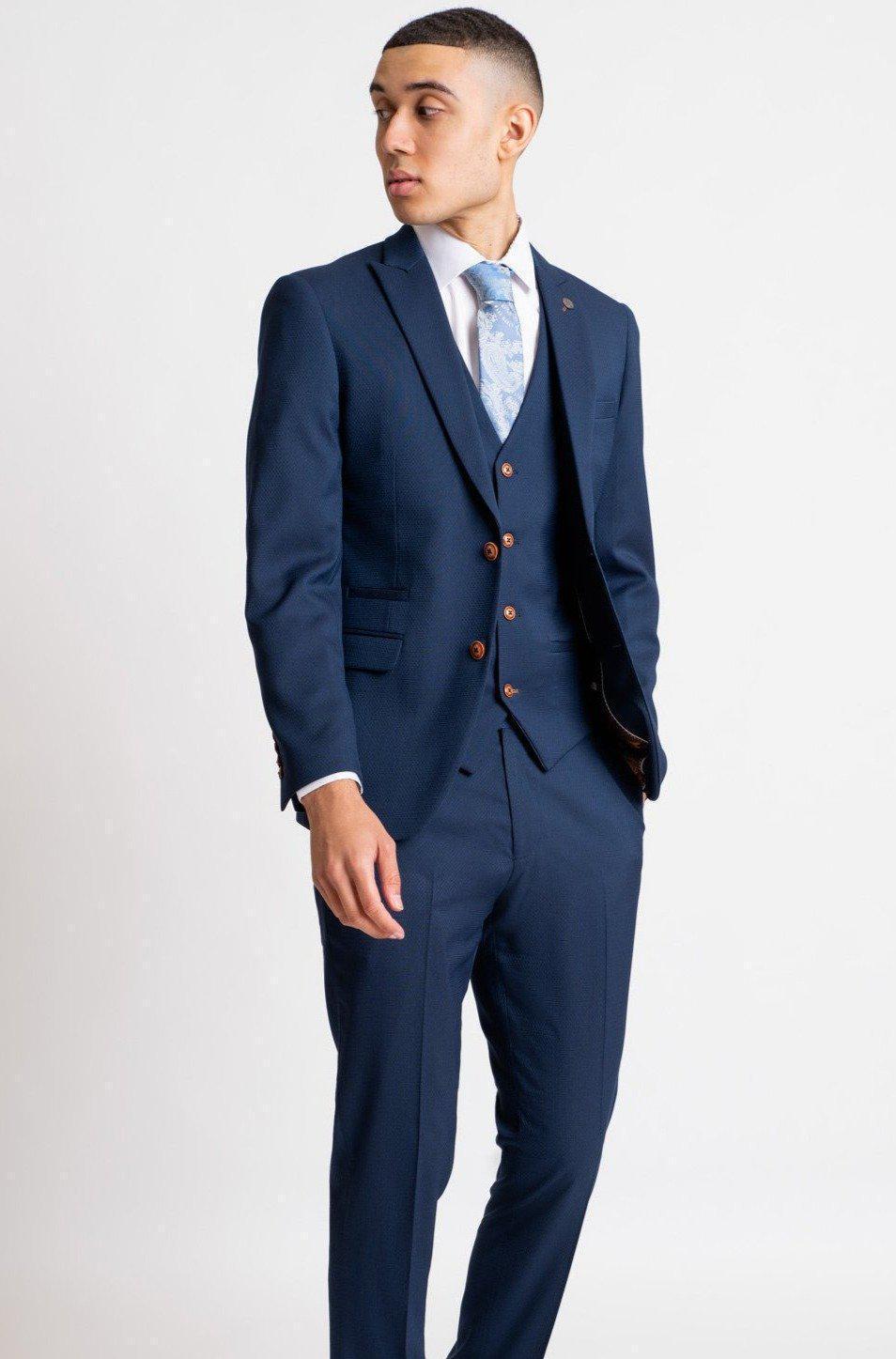 Dominic Calvert-Lewin models marcdarcy's The Everton Collection MAX Royal Blue Suit, featuring a tailored slim fit blazer and patterned tie, posing confidently against a plain white background.