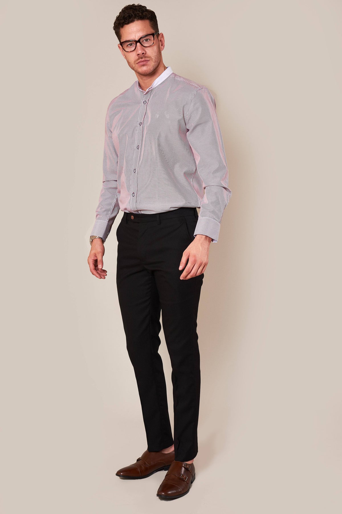 A man in glasses stands against a plain beige background, wearing a diamond print long-sleeve shirt, brown dress shoes, and marcdarcy MAX - Skinny Fit Black Trousers, looking slightly to the side.