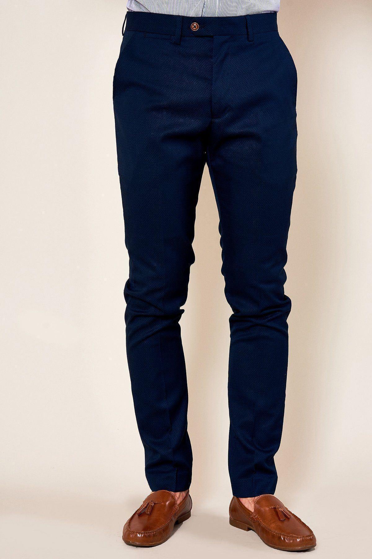 A person wears marcdarcy MAX - Skinny Fit Navy Trousers with a subtle diamond print and brown leather loafers, standing against a plain light background. Only the lower half of their body is visible.