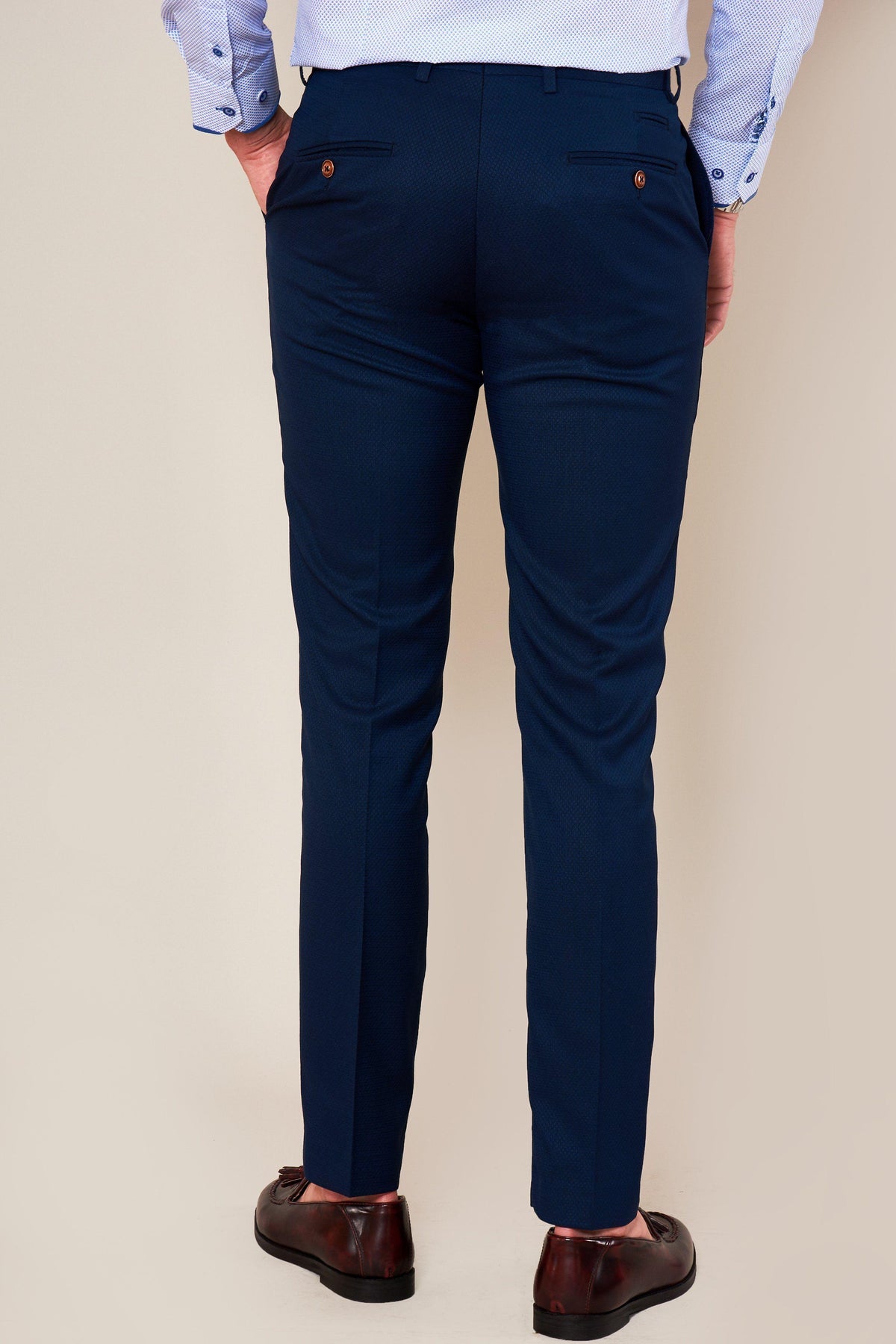 A person wearing marcdarcy’s MAX Skinny Fit Royal Blue Trousers, a light blue dress shirt, and brown shoes is shown from the back against a plain light background—an ideal smart office look.