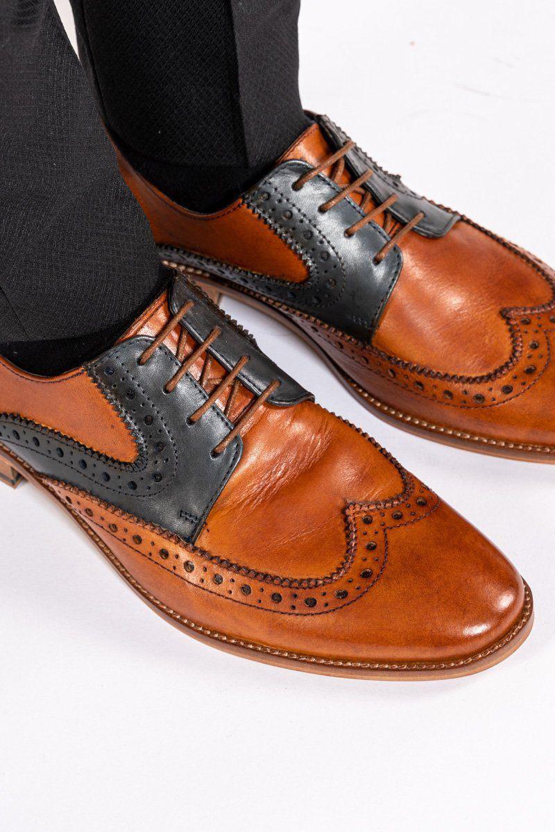 A close-up of the Marc Darcy RILEY Tan Navy Leather Contrast Oxford Brogue Shoes, featuring detailed perforations and laces, styled with black pants against a white background.