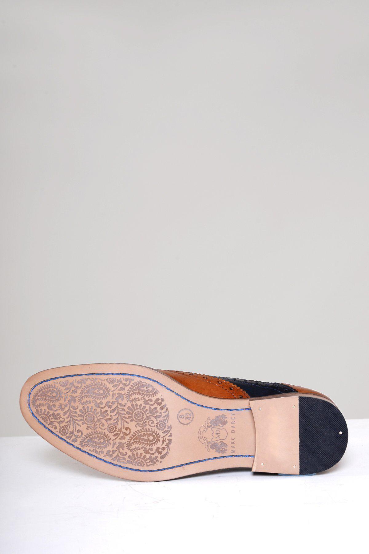 The Marc Darcy RILEY Tan Navy Leather Contrast Oxford Brogue Shoe features a sole with intricate floral engravings, classic oxford and brogue styling, a contrasting leather and rubber heel, and is crafted from vegetable tanned leathers.
