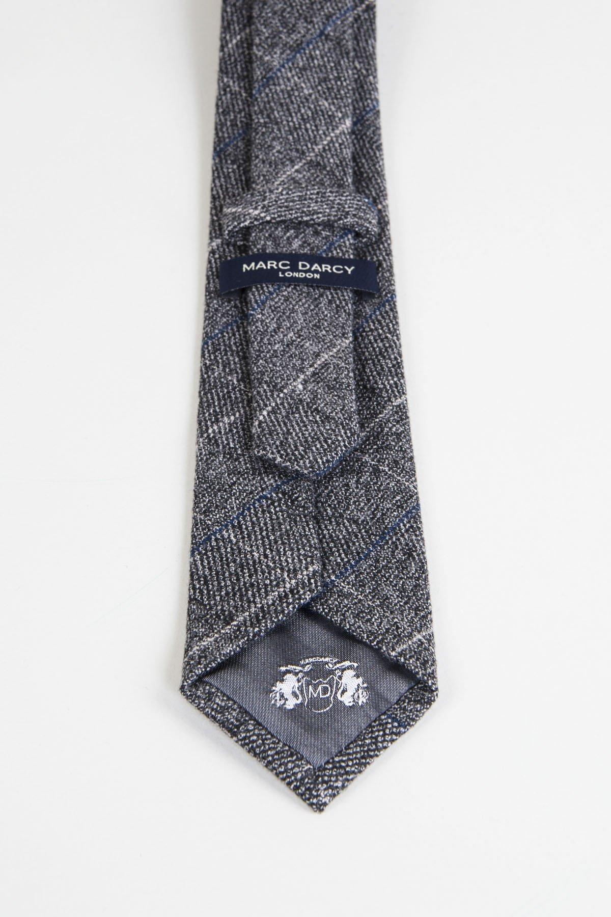 The SCOTT - Grey Tweed Check Tie by Accessory features a classic plaid pattern, ideal for complementing a Scott suit or upgrading your formal look. Finished with a dark blue MARC DARCY LONDON label.