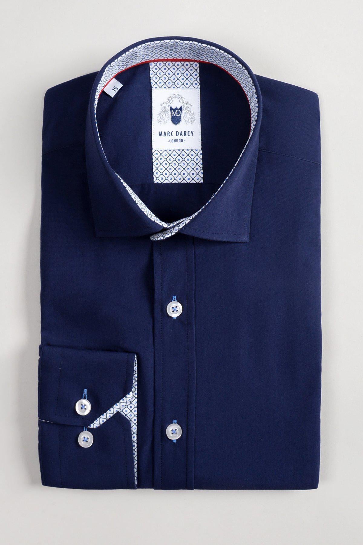 The marcdarcy SERGIO Navy Long Sleeve Shirt features cotton-blend fabric, patterned inner collar and cuffs, white buttons, and a visible marcdarcy label. It is neatly folded and displayed on a light gray background.