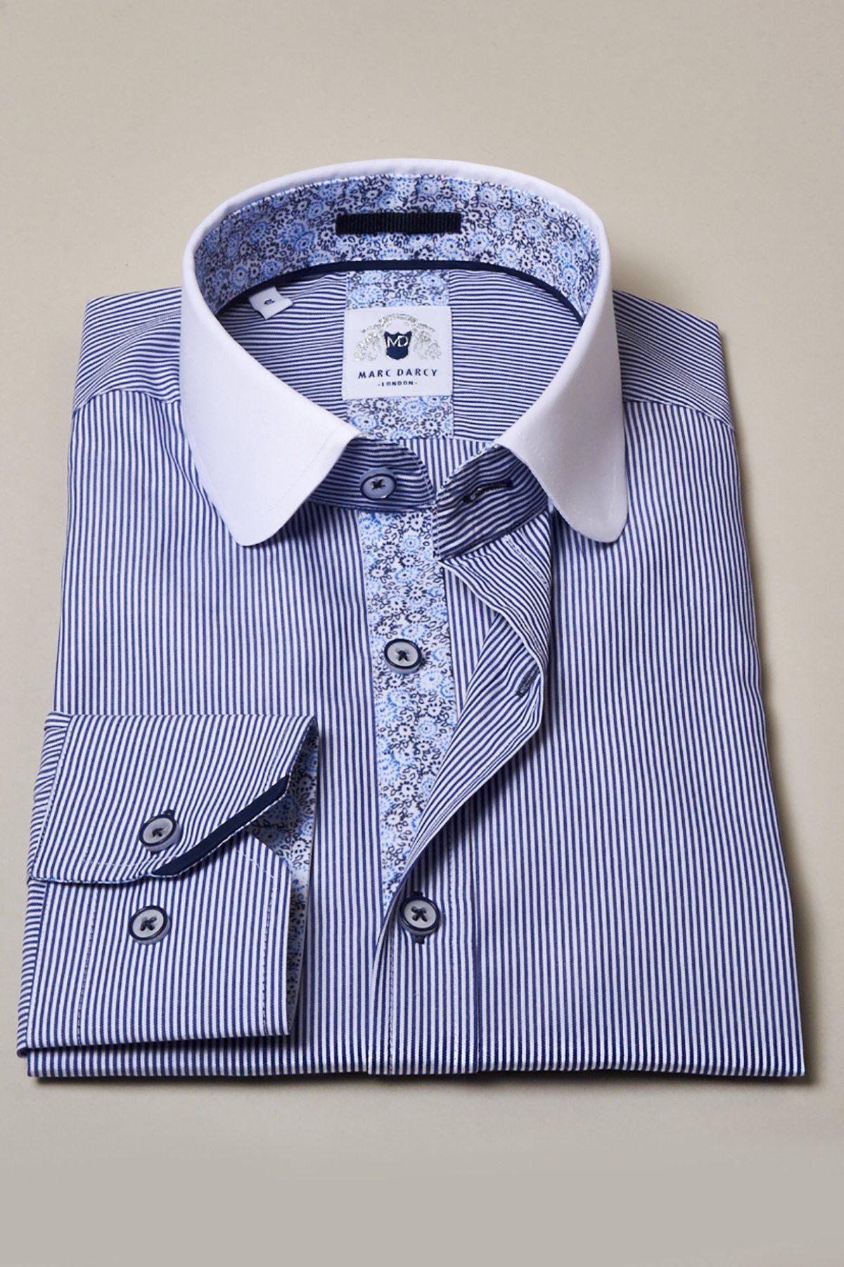 The Marc Darcy SHELBY Navy Blue Stripe Penny Collar Shirt features white collar and cuffs with a floral-patterned inner collar and button placket, evoking classic Tommy Shelby style, displayed on a beige surface.
