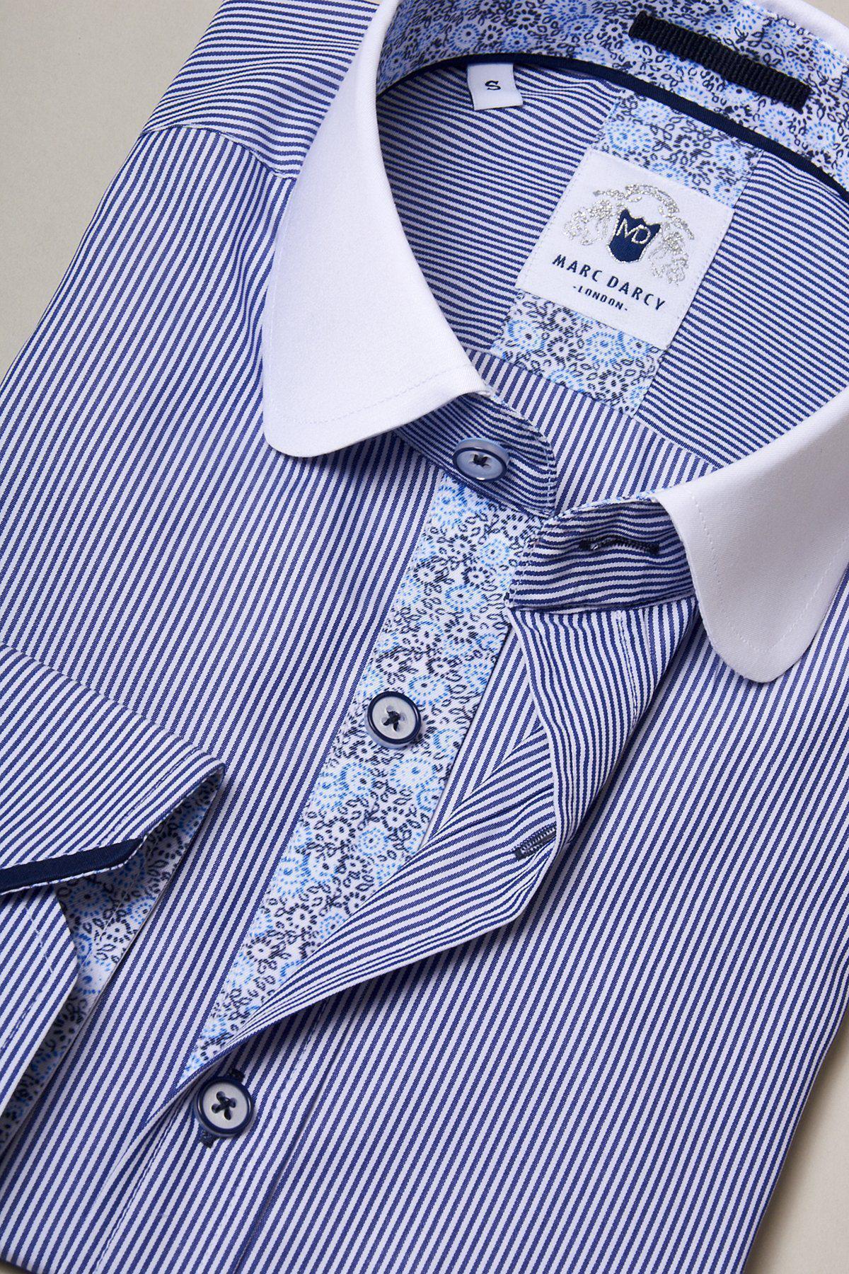 A folded SHELBY Navy Blue Stripe Penny Collar Shirt by Marc Darcy features white stripes, a white penny collar, floral inner placket, and matching buttons. The label displays “Marc Darcy.”.