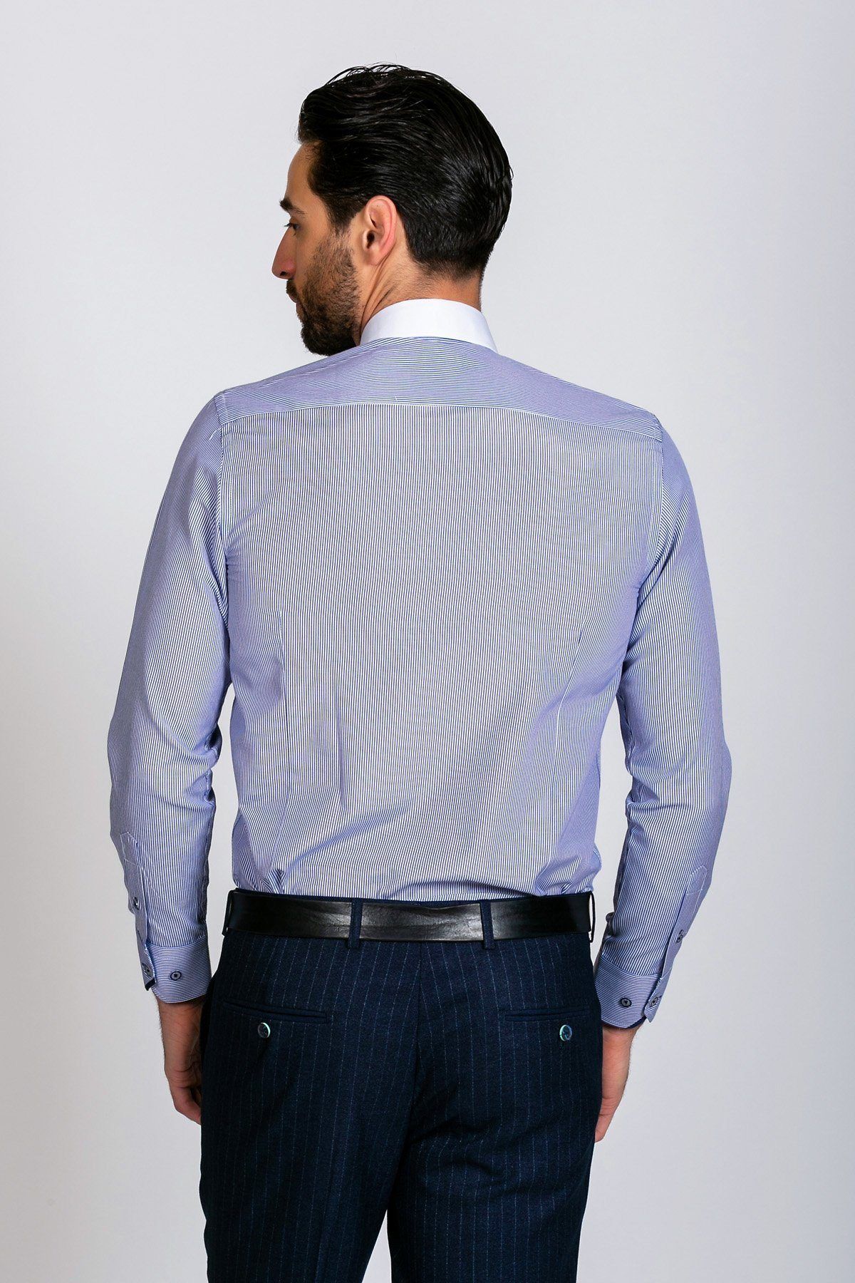 A style-conscious gent with dark hair is seen from behind wearing the Marc Darcy SHELBY Navy Blue Stripe Penny Collar Shirt, paired with dark pinstriped trousers and a black belt against a plain, light background.