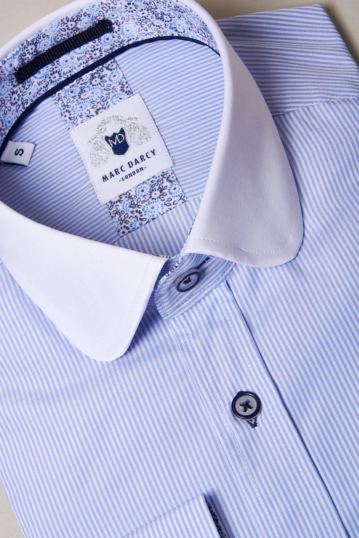 The SHELBY - Sky Blue Stripe Penny Collar Shirt by Marc Darcy features light blue and white stripes, a plain white penny collar, floral inner collar detail, and is made from high cotton content fabric. Label reads Marc Darcy London.