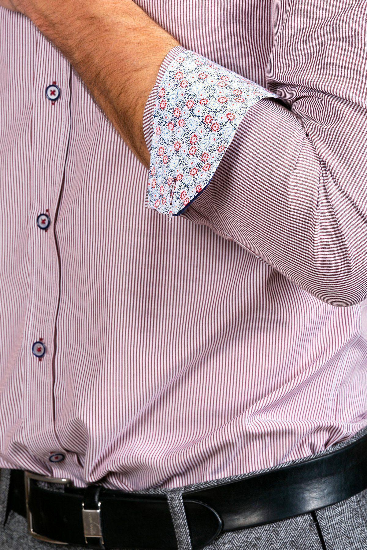 A style-conscious gent wears the SHELBY Wine Stripe Penny Collar Shirt by Marc Darcy, featuring floral inner cuffs, paired with grey pants and a black leather belt. The shirt is partially unbuttoned and his left arm is bent.