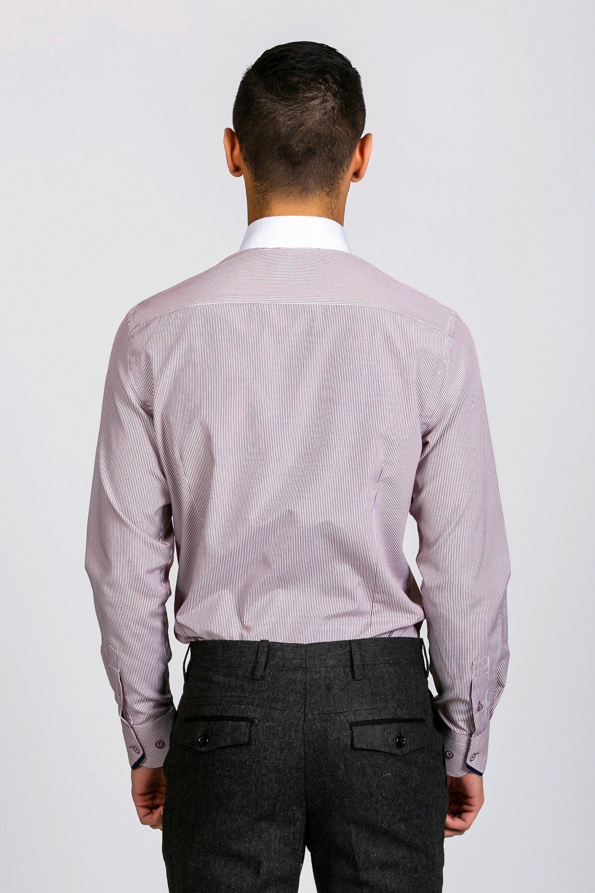 A style-conscious gent faces away from the camera in a Marc Darcy SHELBY Wine Stripe Penny Collar Shirt and dark gray dress pants, set against a plain light background.