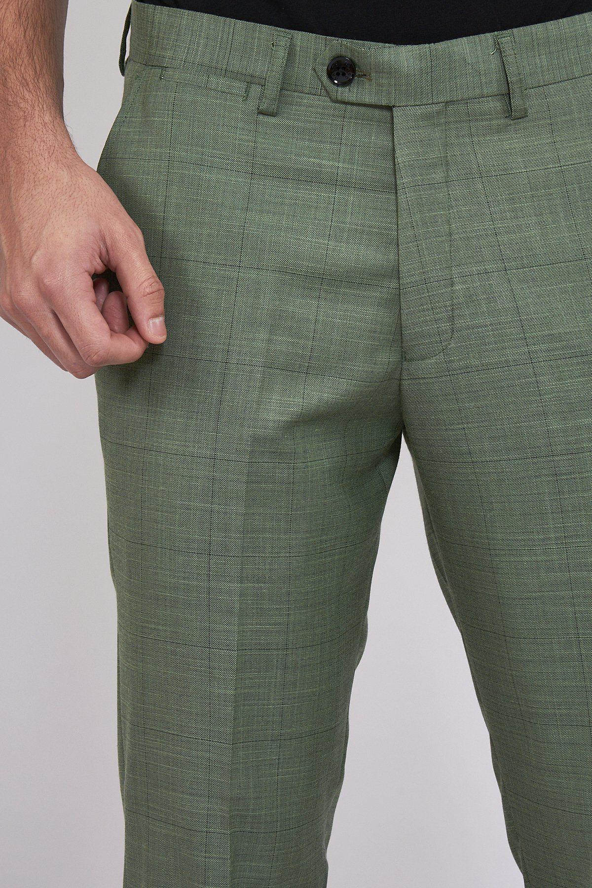 A person wears marcdarcys SID - Moss Green Check Trousers, featuring a black button and belt loops, standing with one hand near the waistband against a plain background.