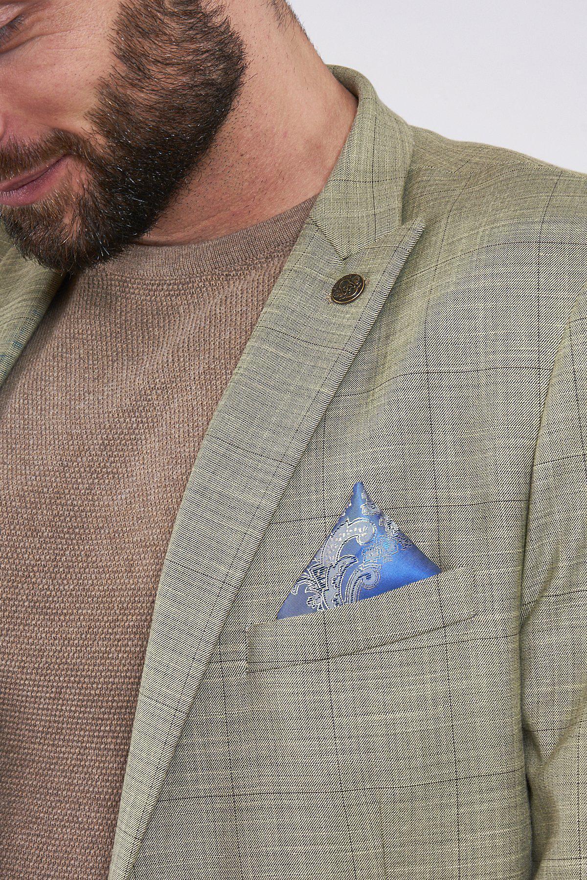 A man wears the marcdarcy SID - Mustard Beige Check Blazer in a slim fit over a tan sweater, accented with a blue paisley pocket square in the breast pocket.