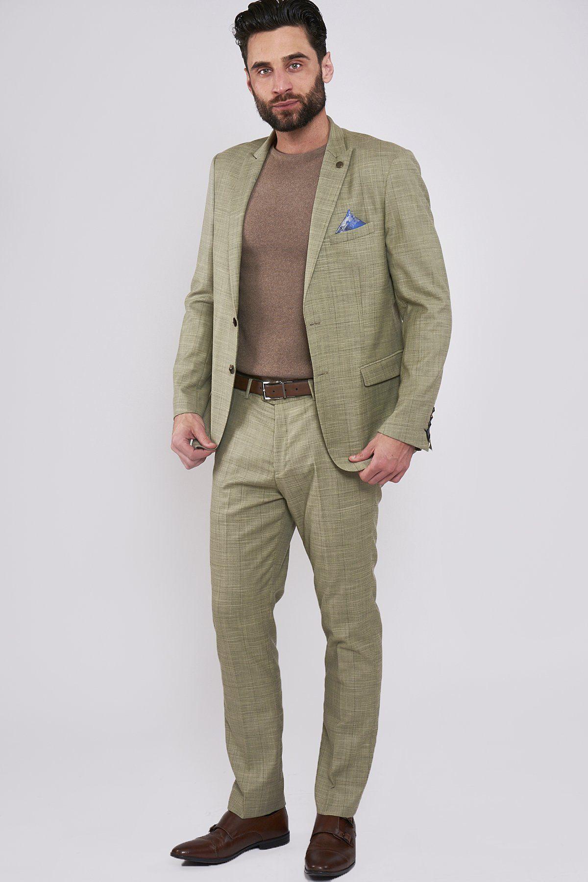A man wears the marcdarcy SID Mustard Beige Check Blazer, styled with a brown crew-neck sweater and brown leather shoes. A blue pocket square accents his jacket, adding flair to his sharp ensemble.