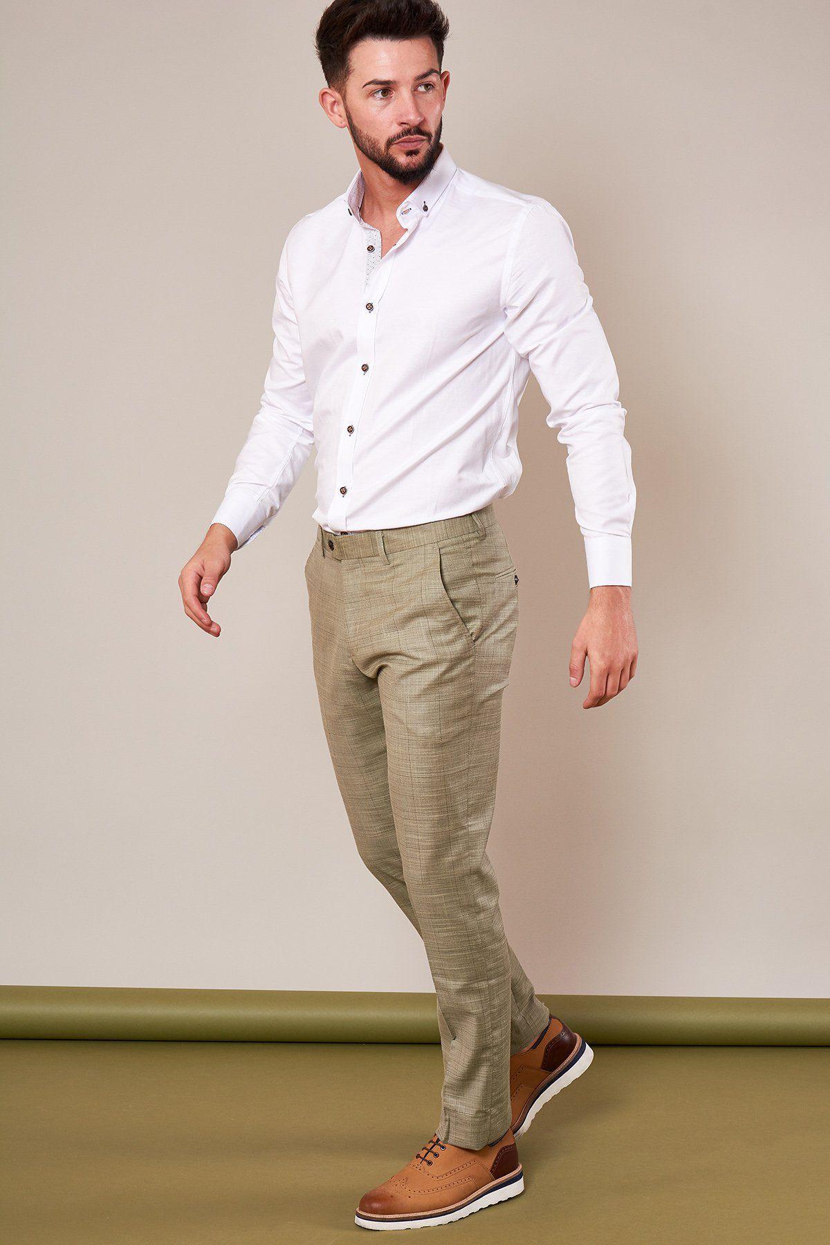 A man in a white button-up shirt, marcdarcy SID - Mustard Beige Check Trousers, and brown dress shoes walks against a neutral background, looking slightly to his left.
