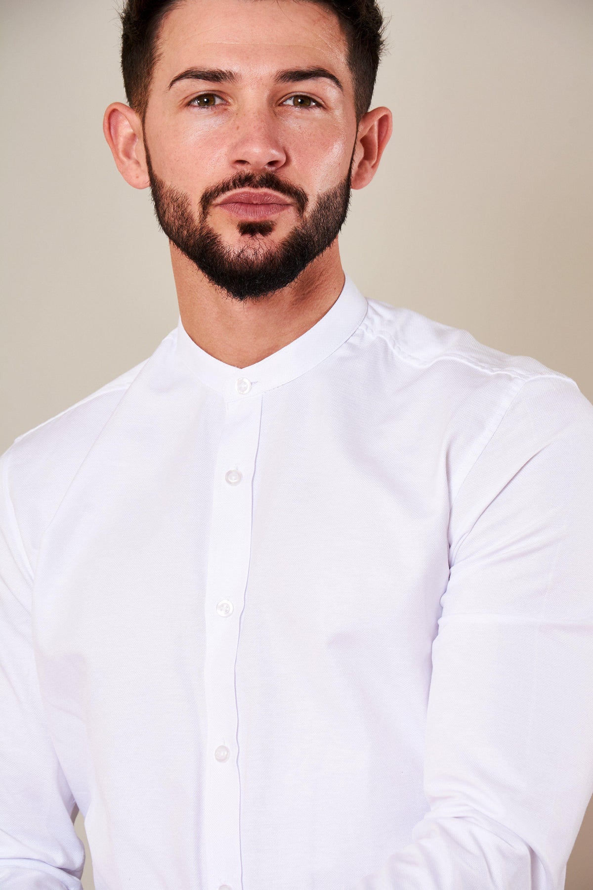 A man with short dark hair and a trimmed beard models the Marc Darcy THOMAS White Grandad Collar Shirt, standing against a plain light background and looking confidently at the camera.