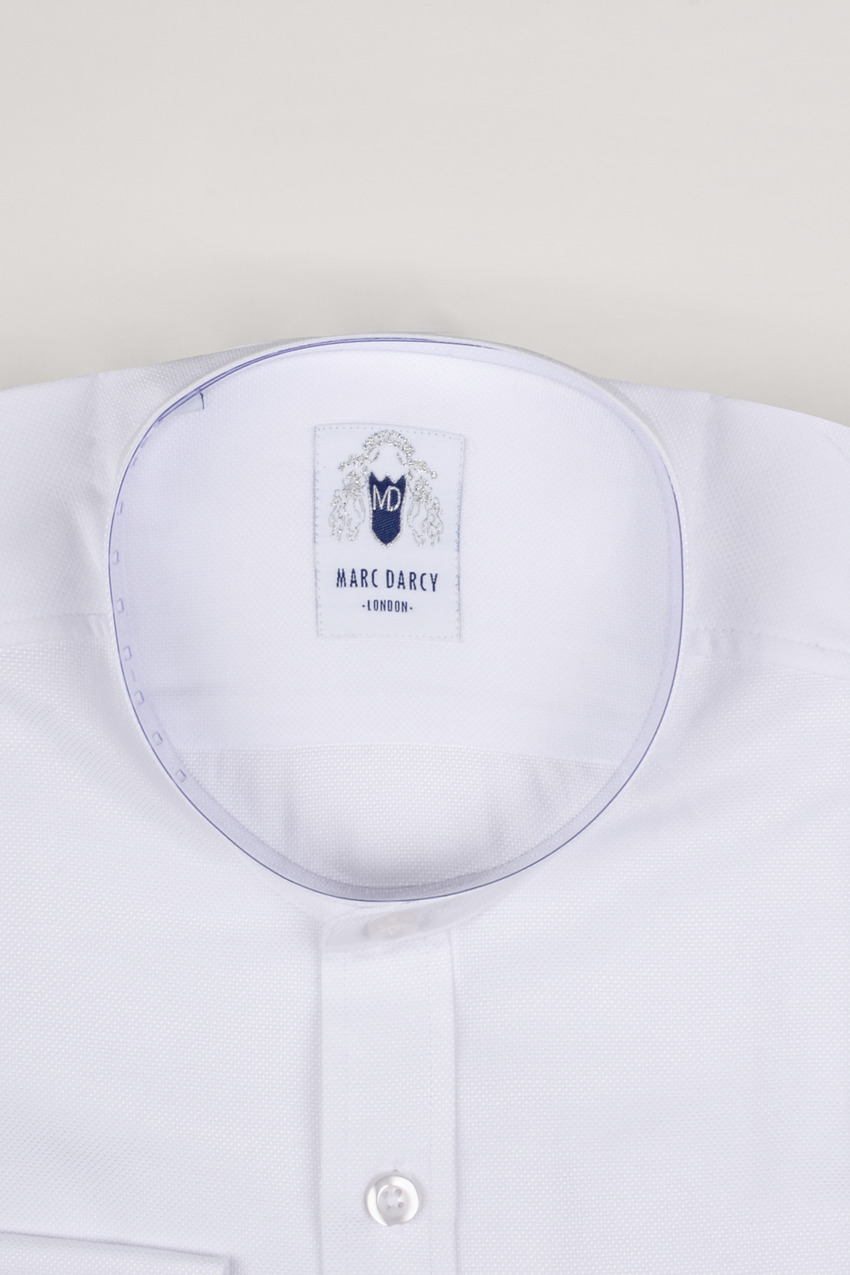 A close-up of the THOMAS - White Grandad Collar Shirt by Marc Darcy, featuring a subtle textured cotton blend fabric, white buttons, a visible collar, and a Marc Darcy label sewn inside the neck.