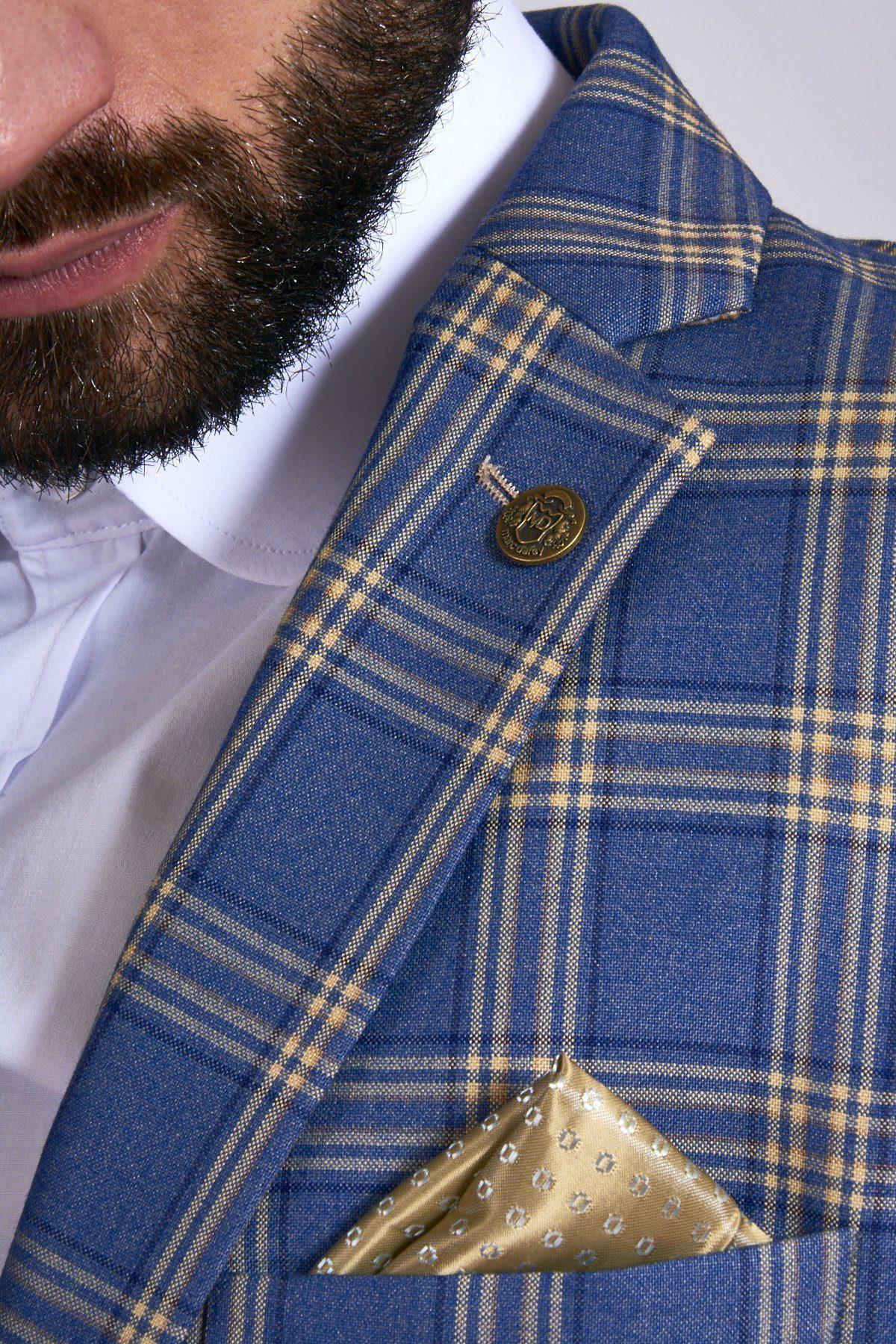A close-up of a bearded man in the marcdarcy TONY Blue Yellow Check Suit with a single-breasted waistcoat, white shirt, golden pocket square, and a gold button on his lapel.