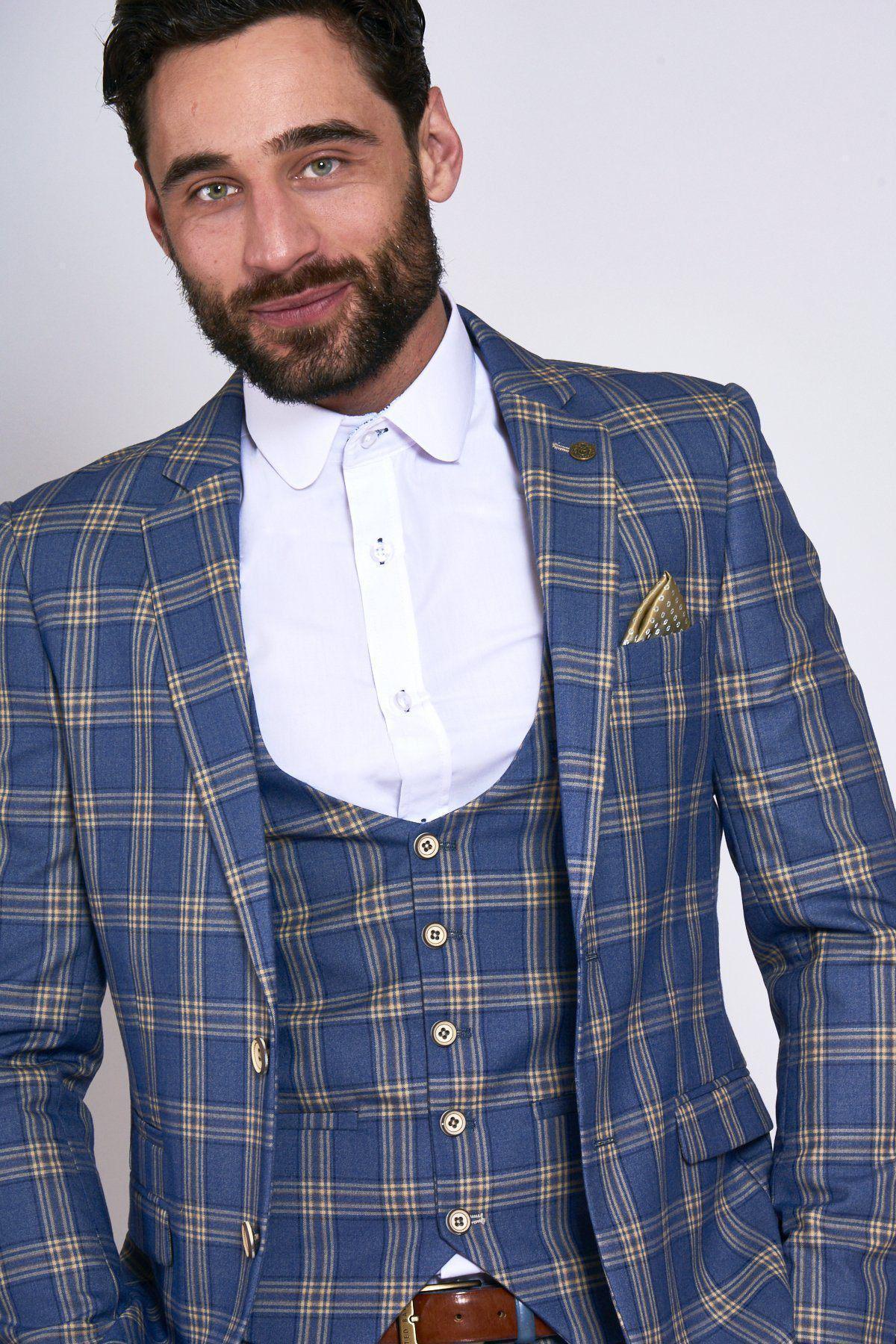 A bearded man wears the marcdarcy TONY Blue Yellow Check Suit with Single Breasted Waistcoat, paired with a white dress shirt and tan pocket square, standing against a plain light background and smiling slightly at the camera.