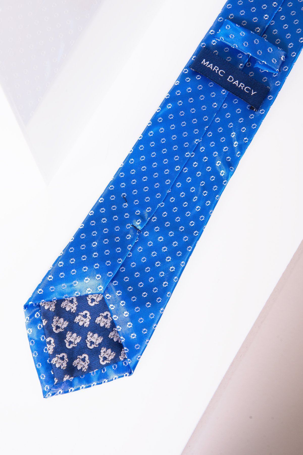 The Marc Darcy TS TUBES Blue Spot Tie and Pocket Square Set features a luxury blue tie with small white dots and a contrasting floral tip, displayed on a white surface.