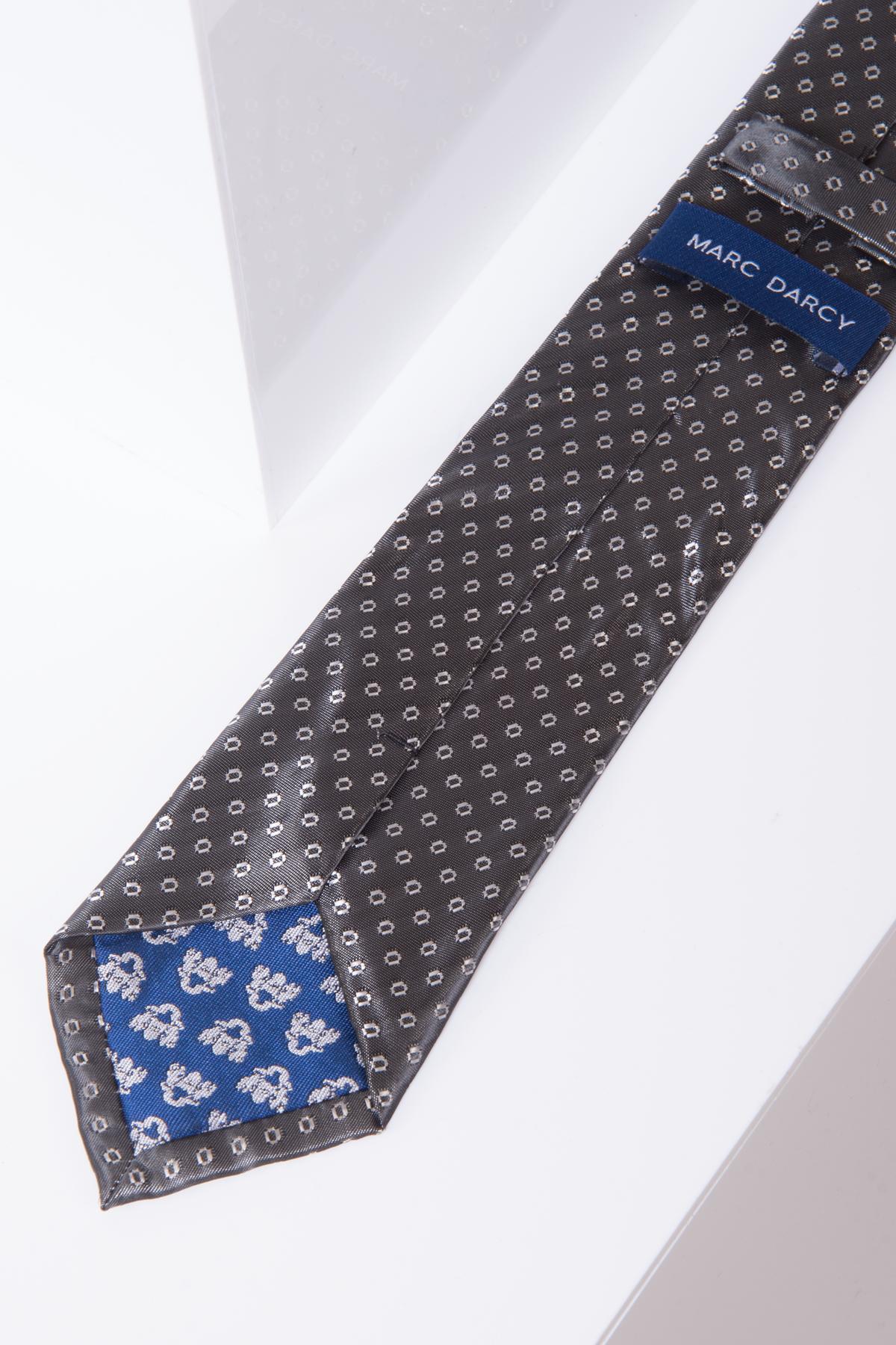 A close-up of the TS TUBES - Grey Spot Tie and Pocket Square Set by Marc Darcy, showcasing its silk-style texture, blue brand label, and contrasting blue floral inner tip. Displayed on a white surface, it's ideal for elevating any formal outfit.